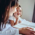 Nanny and child reading book and laughing together