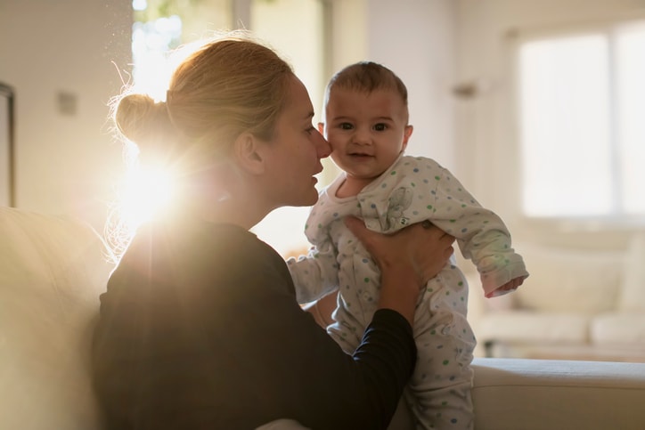 A mother lovingly holds up her baby 