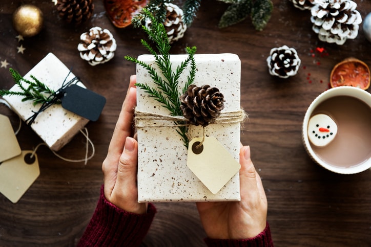 Directly Above View Of Hand Holding Christmas Present Over Table