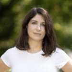 Laura Norkin headshot outdoors wearing white tee shirt.